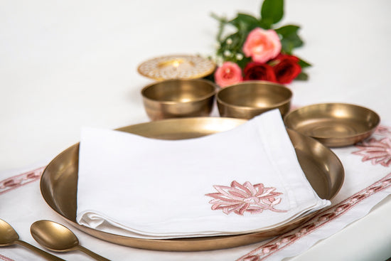 White linen placemats and white linen napkins with lotus embroidery.