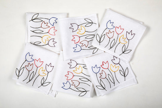 White linen cocktail napkins with floral embroidery.