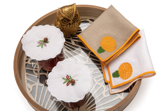 White linen cocktail napkins with embroidered marigold.