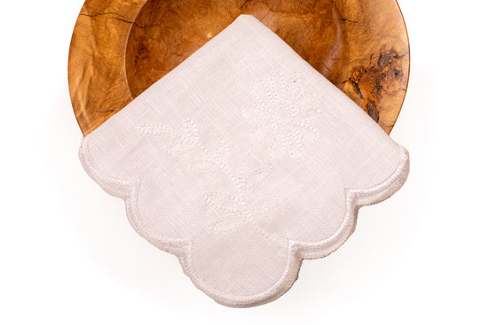 White linen scalloped and embroidered dinner napkin.