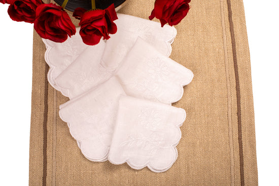 White linen scalloped and embroidered cocktail napkin.