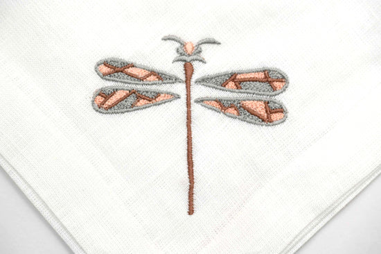 White linen dinner napkins with dragonfly embroidery.