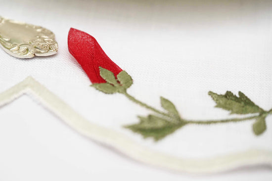 Round linen placemats and napkins with rosebud embroidery.