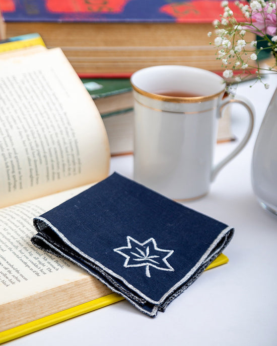 Navy blue linen cocktail napkins with silver maple leaf embroidery.