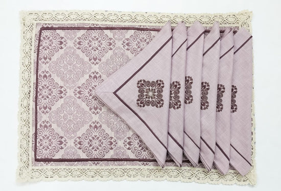 Pink printed placemats with pink embroidered linen napkins with lace.