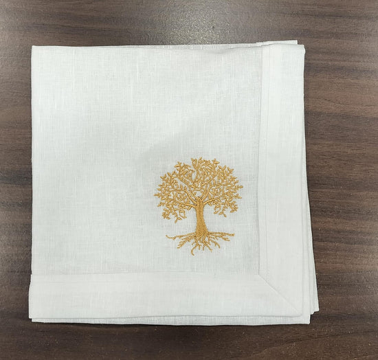 White linen dinner napkins with tree embroidery.