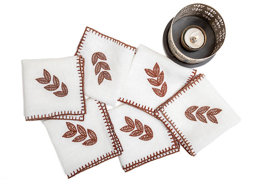 White linen dinner napkins with brown leaf embroidery.