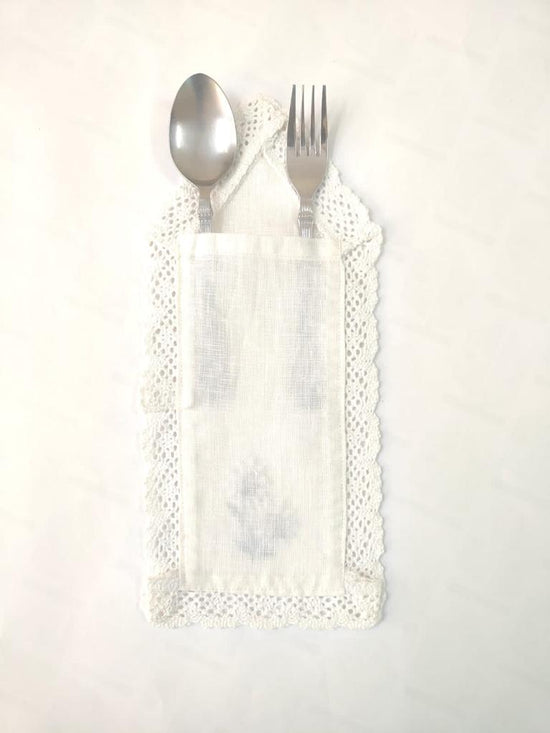 White linen cutlery holder with floral embroidery.
