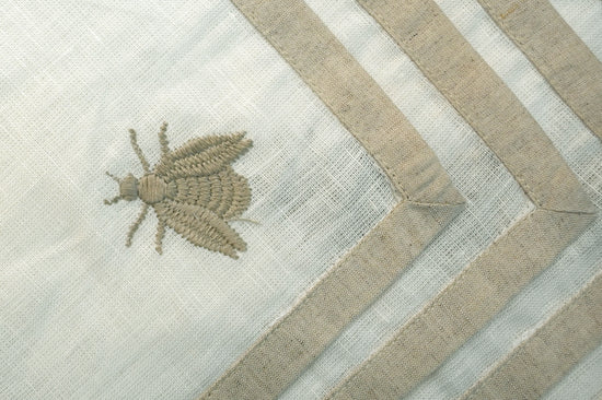 White linen cocktail napkins with an embroidered beetle