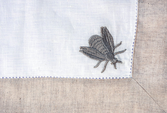 White linen placemat & napkins with beetle embroidery.