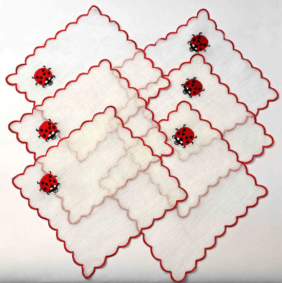 White linen cocktail napkins with beetle embroidery.