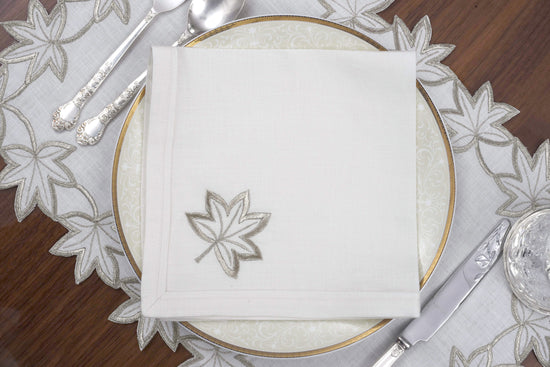 White linen placemats and napkins with gold cutwork embroidery.