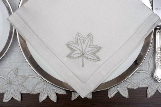 White linen placemats and napkins with silver cutwork embroidery.