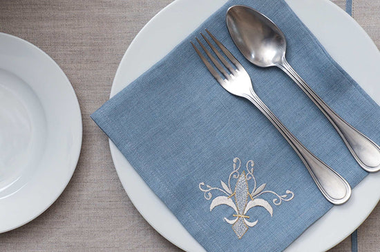 Natural linen placemats with blue embroidered napkins .