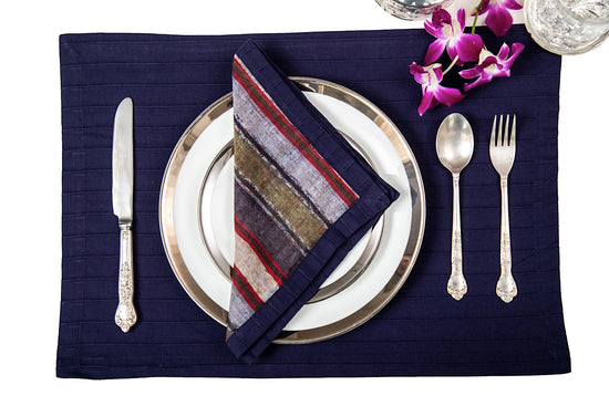 Navy blue linen pleated placemats with blue and red striped linen napkins.
