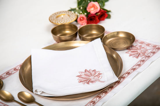 White linen  placemats and white linen napkins with lotus embroidery.