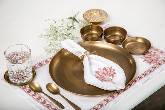 White linen  placemats and white linen napkins with lotus embroidery.