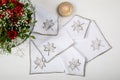 White linen dinner napkins embroidered in gold.