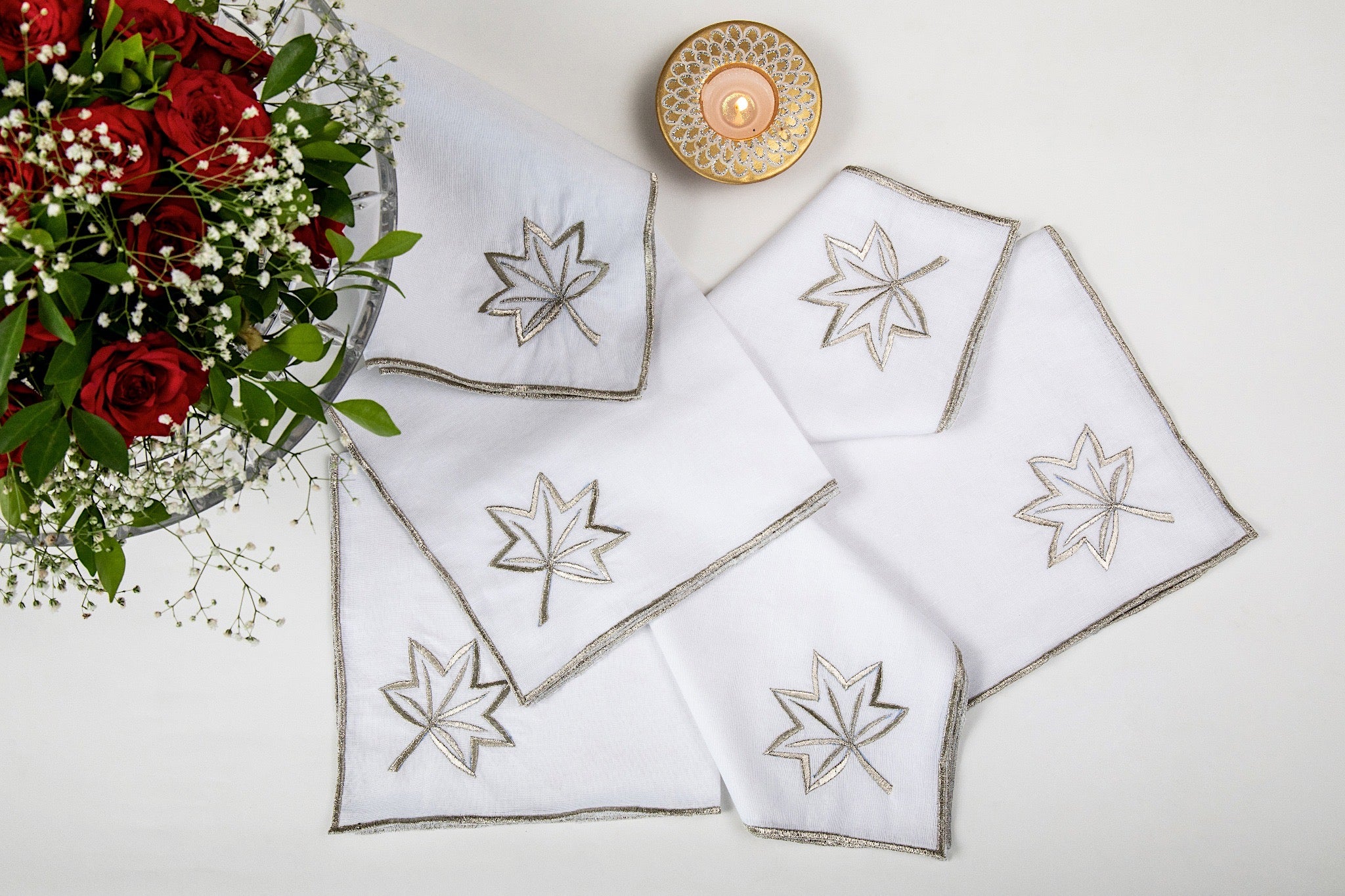 White linen dinner napkins embroidered in gold.