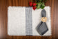 White linen with woven grey striped placemats with grey linen frayed napkins.
