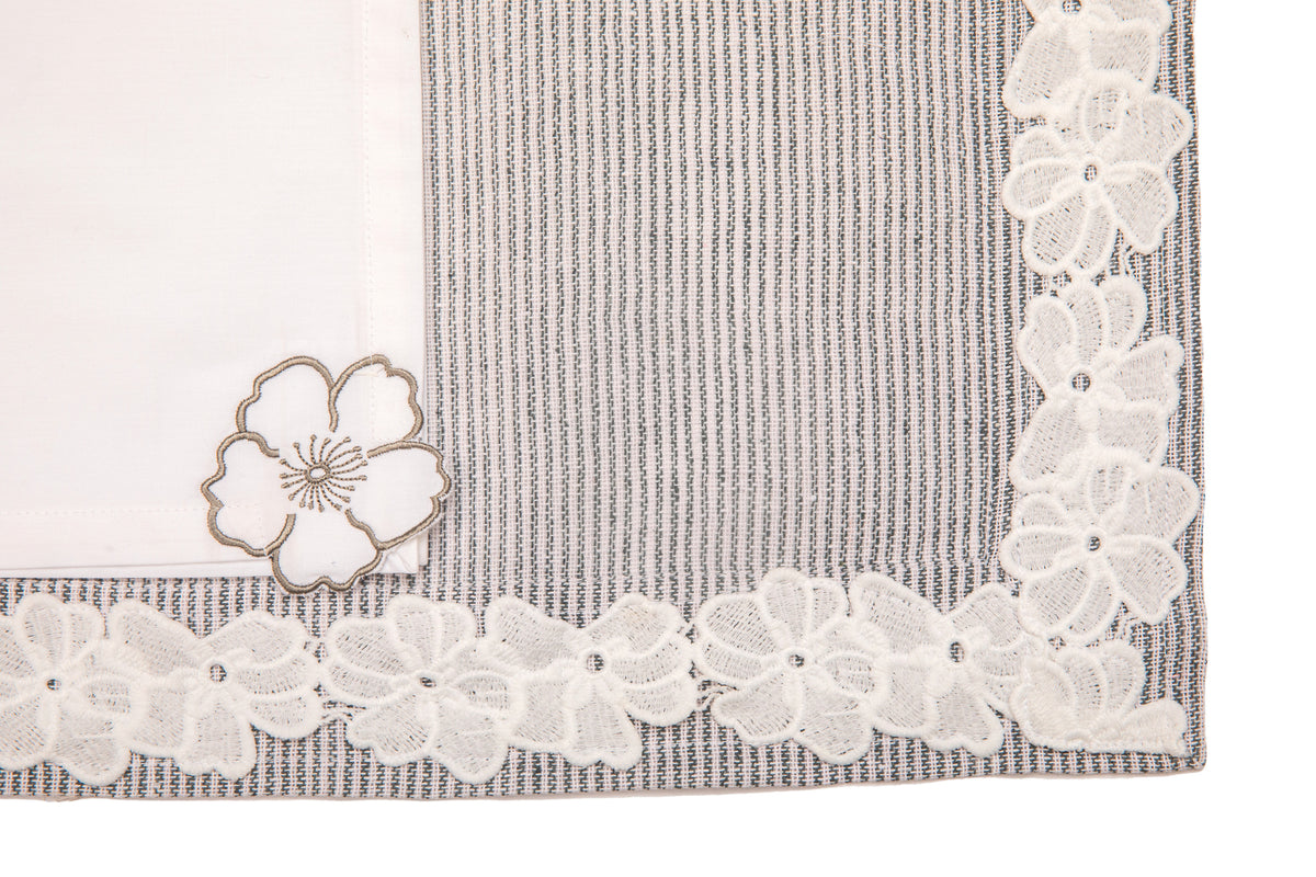 Laced striped placemats  and white linen dinner napkins with floral embroidery.