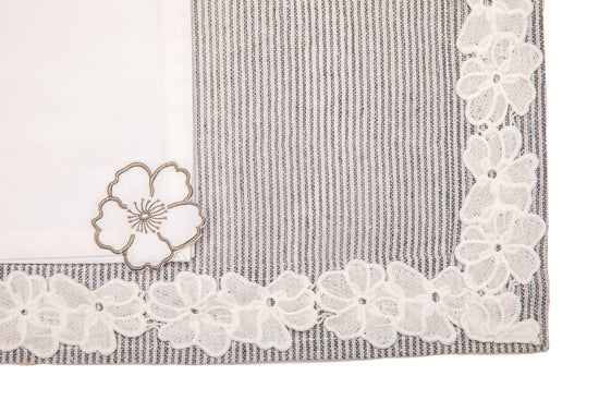 Laced striped placemats  and white linen dinner napkins with floral embroidery.