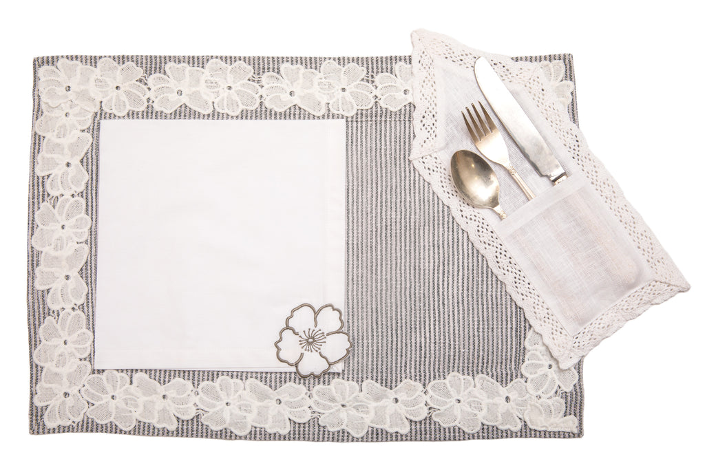 Laced striped placemats  and white linen dinner napkins with floral embroidery.