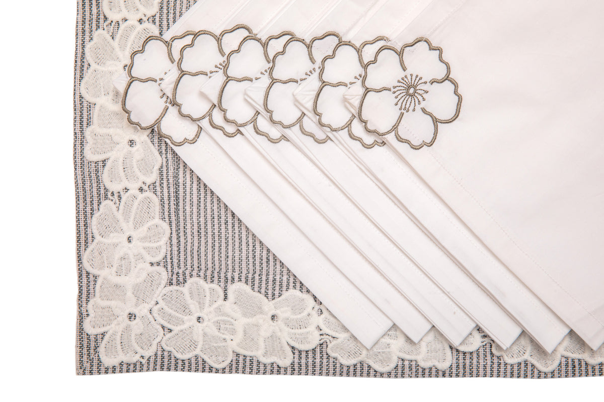 Laced striped placemats  and white linen dinner napkins with floral embroidery.