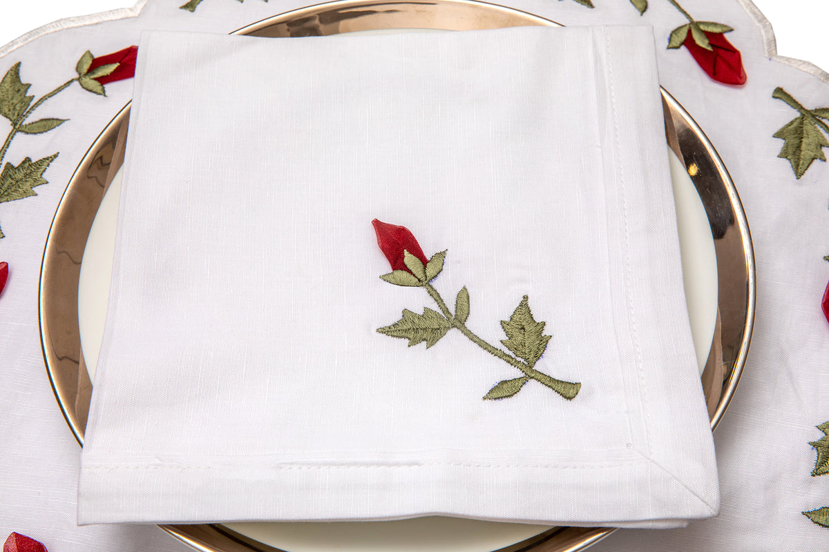 White linen dinner napkins with rosebud embroidery.