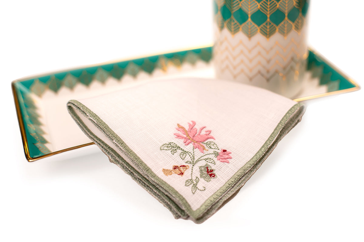 White linen cocktail napkin with mint green floral detailing.