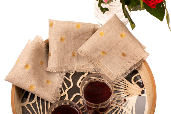Natural linen cocktail napkin with woven gold detailing.