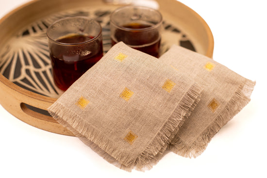 Natural linen cocktail napkin with woven gold detailing.