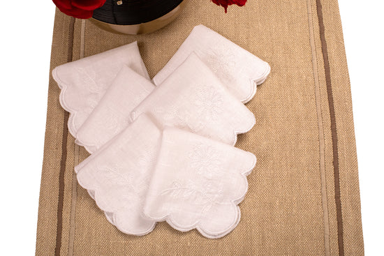 White linen scalloped and embroidered cocktail napkin.