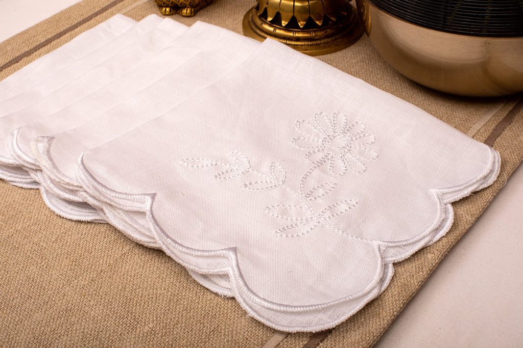 White linen scalloped and embroidered dinner napkin.