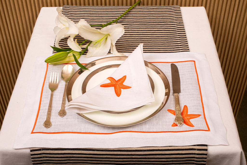 White linen placemat and napkin with striking starfish embroidery.