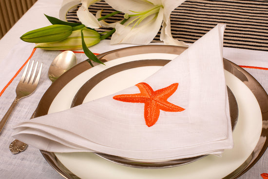 White linen placemat and napkin with striking starfish embroidery.