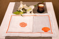 White linen placemat and napkin with striking shells and coral embroidery.