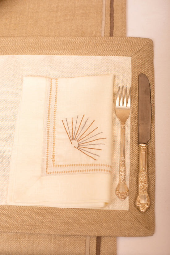 Cream linen placemat with  cream linen embroidered napkin.