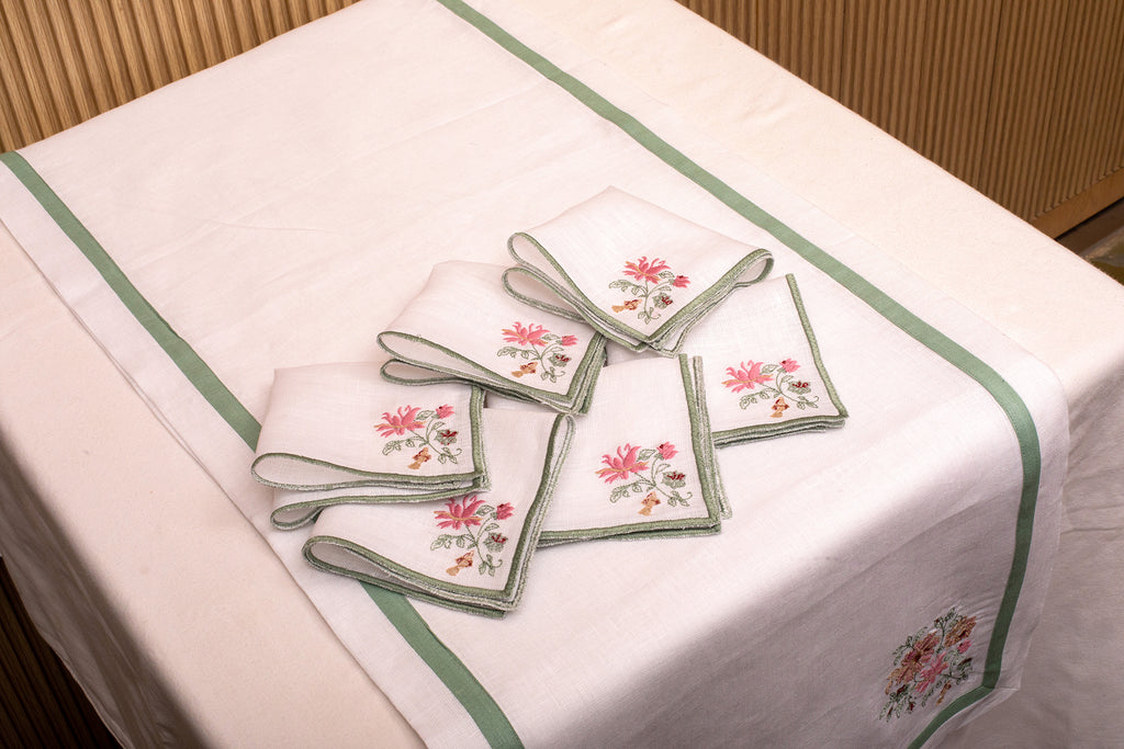 White linen cocktail napkin with mint green floral detailing.