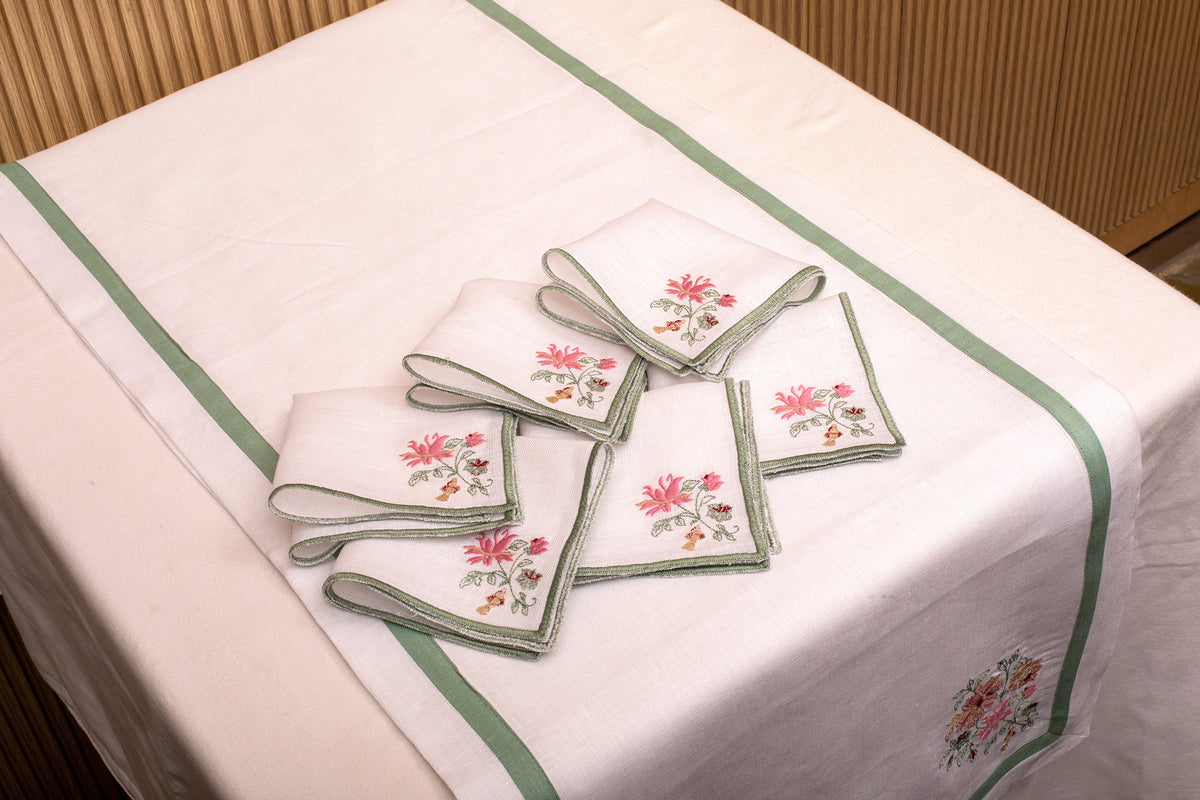 White linen cocktail napkin with mint green floral detailing.