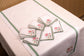 White linen cocktail napkin with mint green floral detailing.
