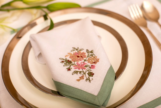 White linen embroidered placemat and napkin with mint green floral detailing.
