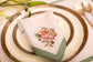 White linen embroidered placemat and napkin with mint green floral detailing.