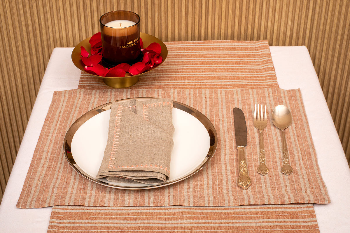 Rust and silver striped linen placemat and beige embroidered linen napkin.