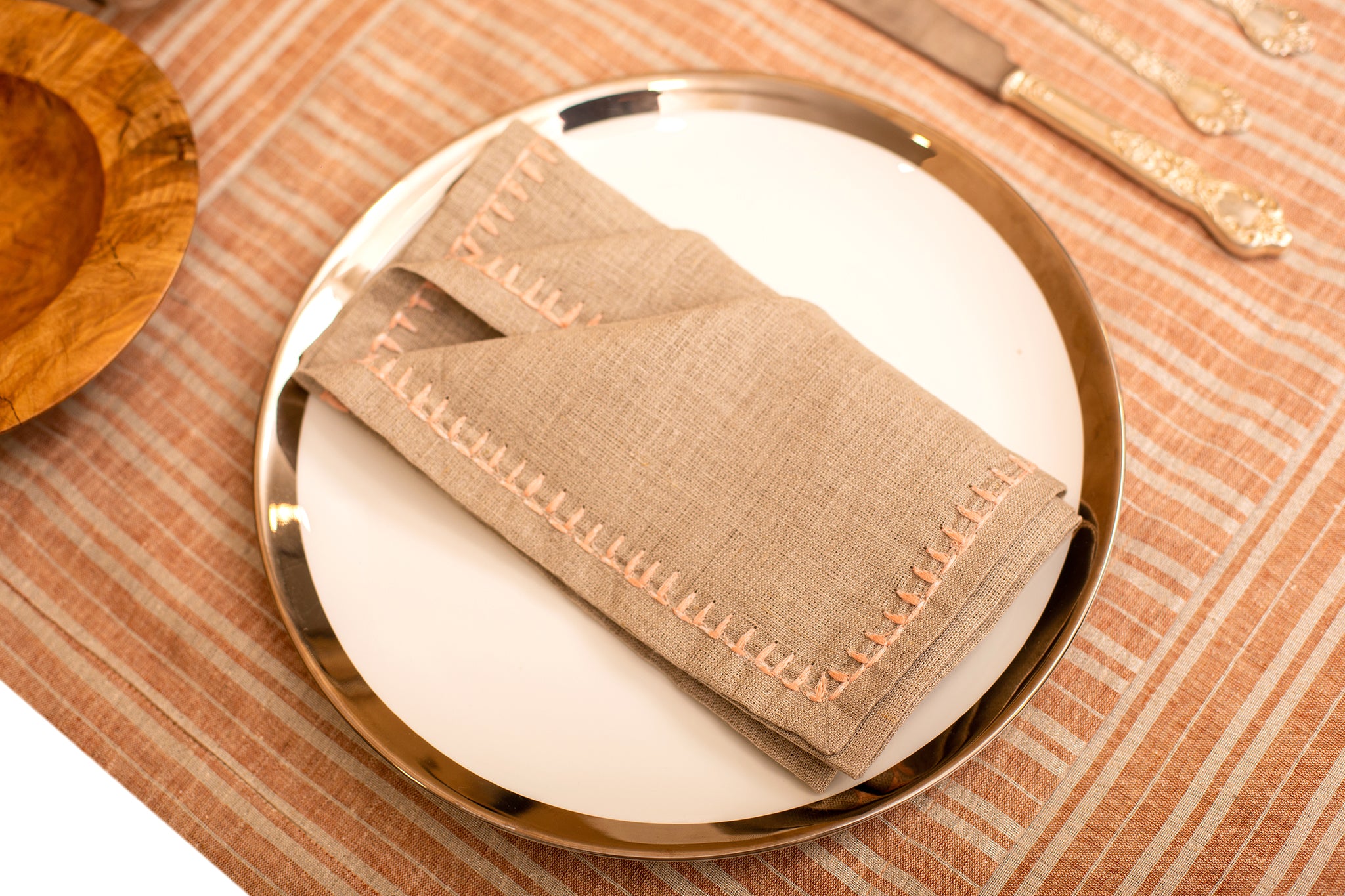 Rust and silver striped linen placemat and beige embroidered linen napkin.
