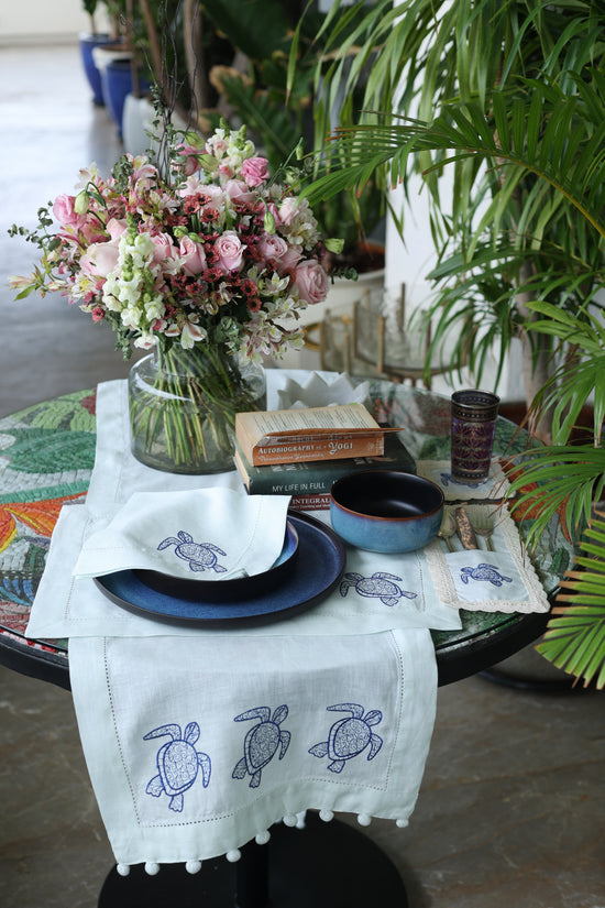 Powder blue linen coaster with embroidered turtle.