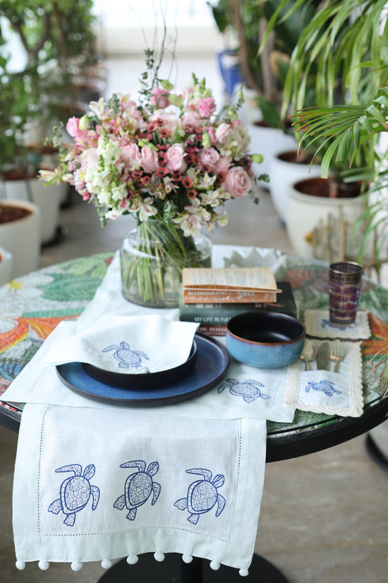Powder blue linen placemats and napkins with embroidered turtle.