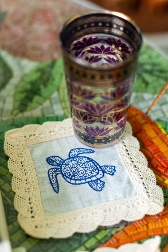 Powder blue linen coaster with embroidered turtle.