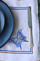 White linen placemats and napkins with embroidered butterfly.