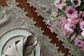 Brown linen runner with gold cutwork embroidery.